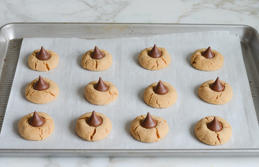 adding Hershey's kisses to partially baked peanut butter blossoms 