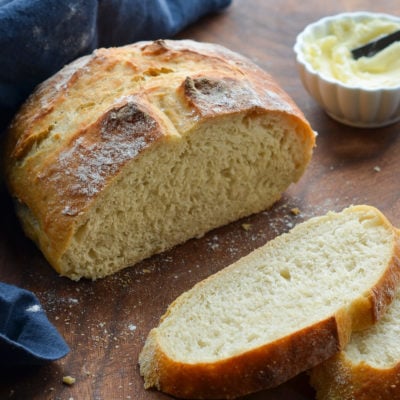 Partially-sliced loaf of crusty artisan bread.