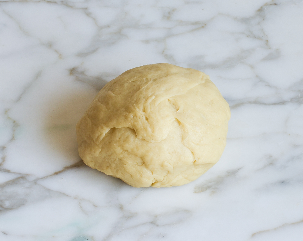 Ball of dough on a marble countertop.