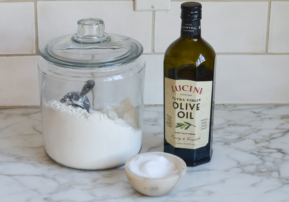 Flour, salt, and olive oil on a countertop.