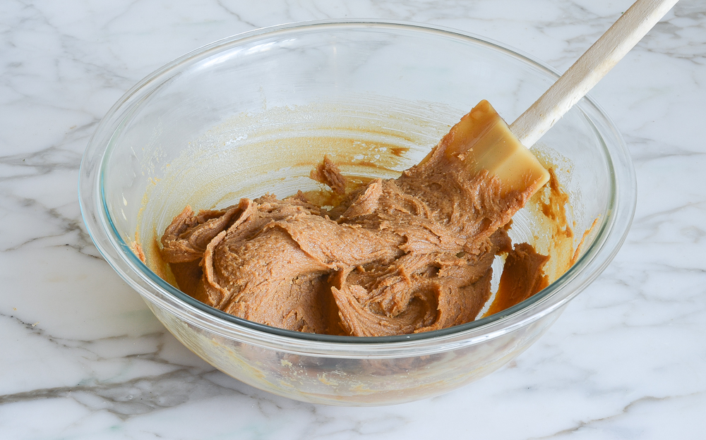 Spatula in a bowl of thick peanut butter dough.