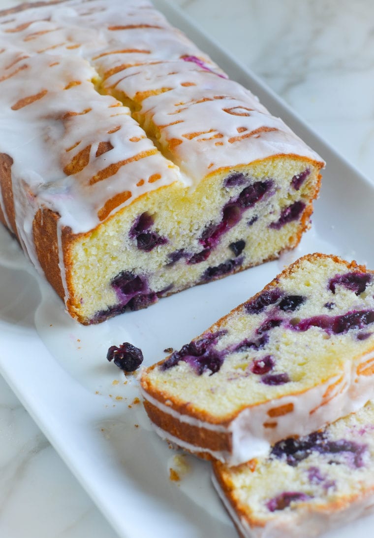 Loaf of lemon blueberry pound cake with some slices removed.
