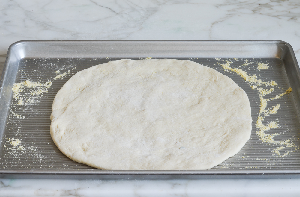 Circle of pizza dough on a baking sheet.