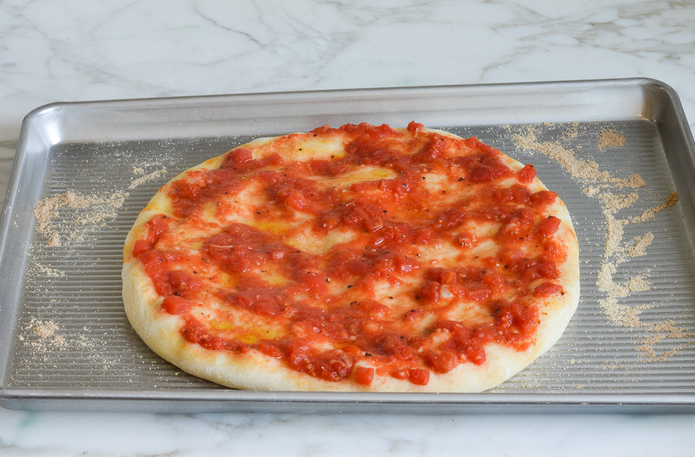 Pizza dough topped with red sauce.