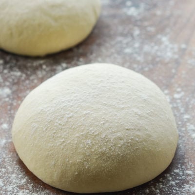 Ball of pizza dough on a floured surface.