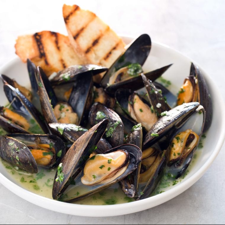 Bowl of oven-steamed mussels with garlic and white wine.