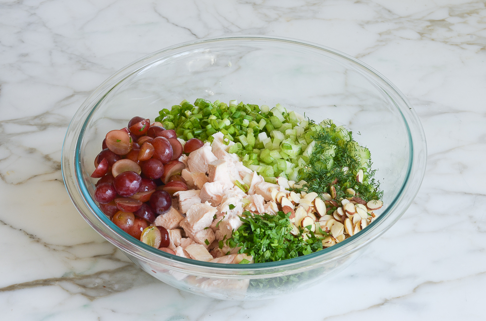 Chicken salad components in a bowl with dressing.