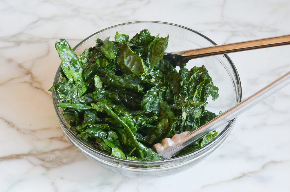 tossed kale in bowl with tongs