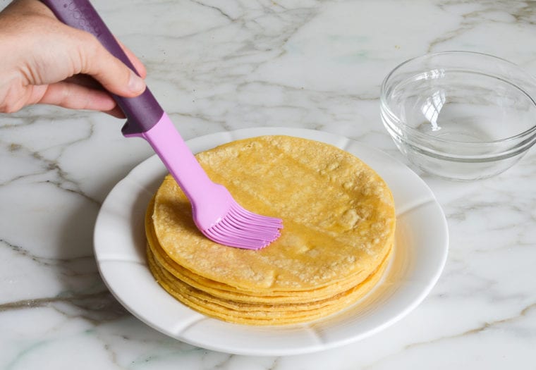 brushing corn tortillas with oil