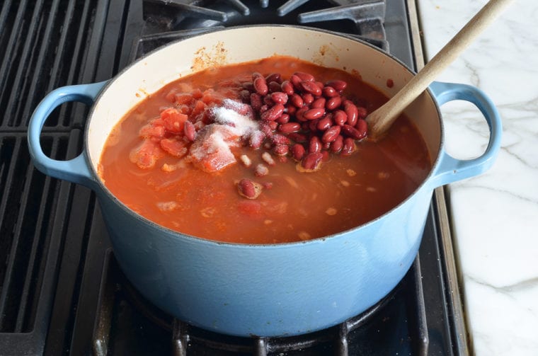 adding tomatoes and beans to the pot