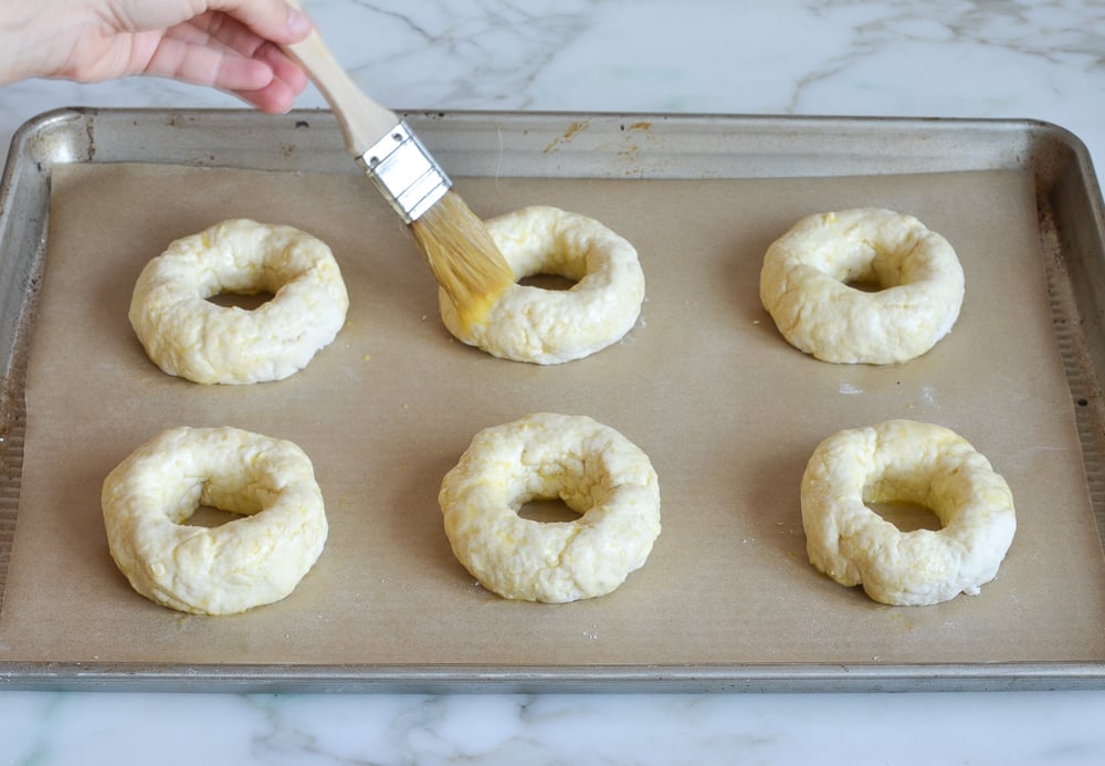 brushing egg wash on bagels