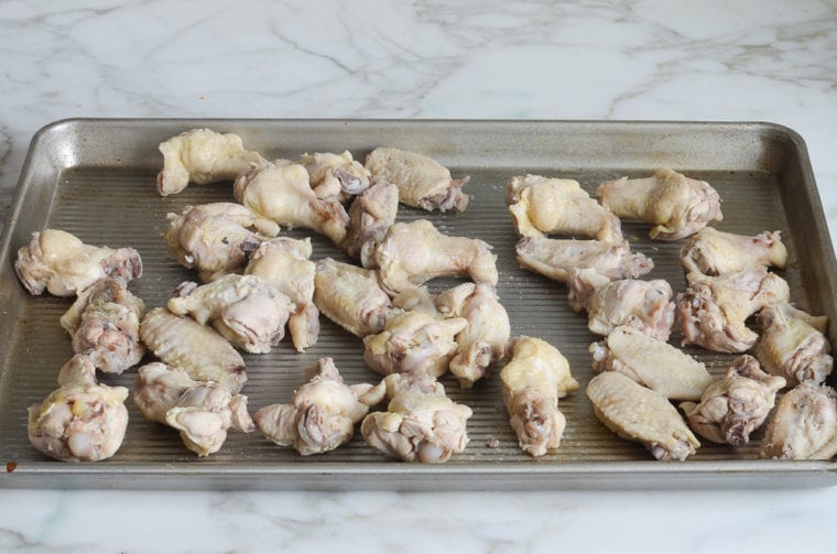drained chicken wings on baking sheet.
