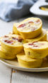 Egg bites with bacon and gruyere piled on a plate.