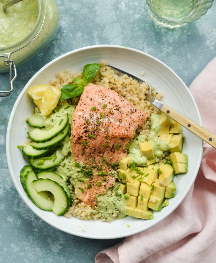 Plate with roasted salmon, quinoa, avocado, cucumber, and green goddess dressing.