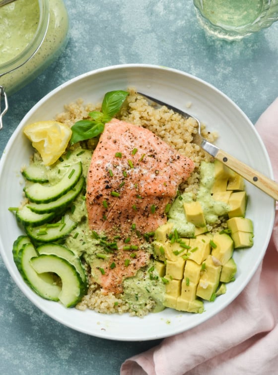 Plate with roasted salmon, quinoa, avocado, cucumber, and green goddess dressing.