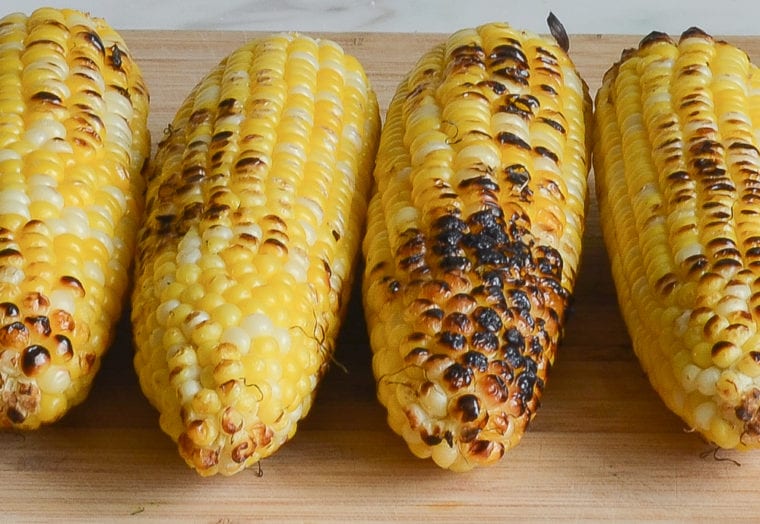 Grilled corn on a cutting board.