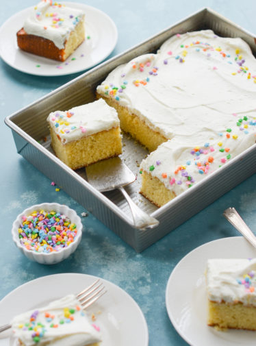 Vanilla sheet cake with cream cheese frosting in a baking dish.