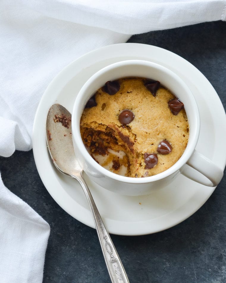 Chocolate chip cookie in a mug, missing a bite.