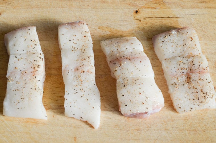 seasoning halibut with salt and pepper