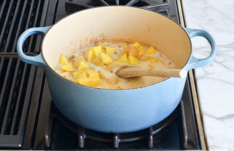 adding broth, milk, potatoes and seasoning to pot