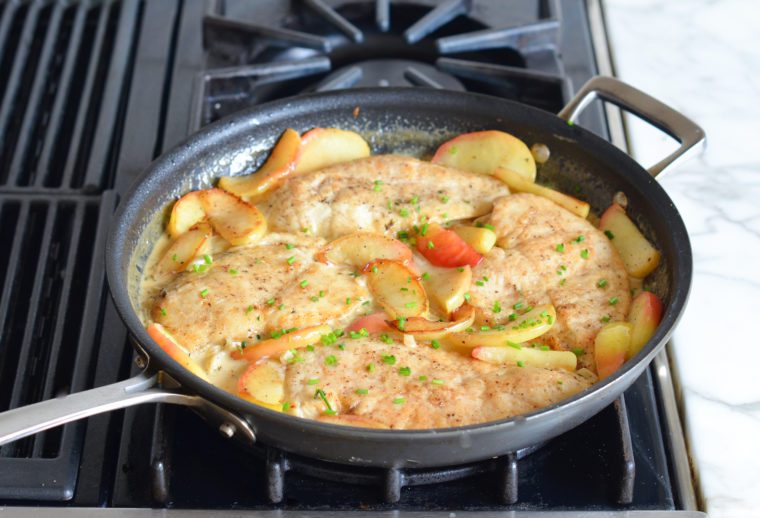 adding apples and cider to chicken fricassee in skillet