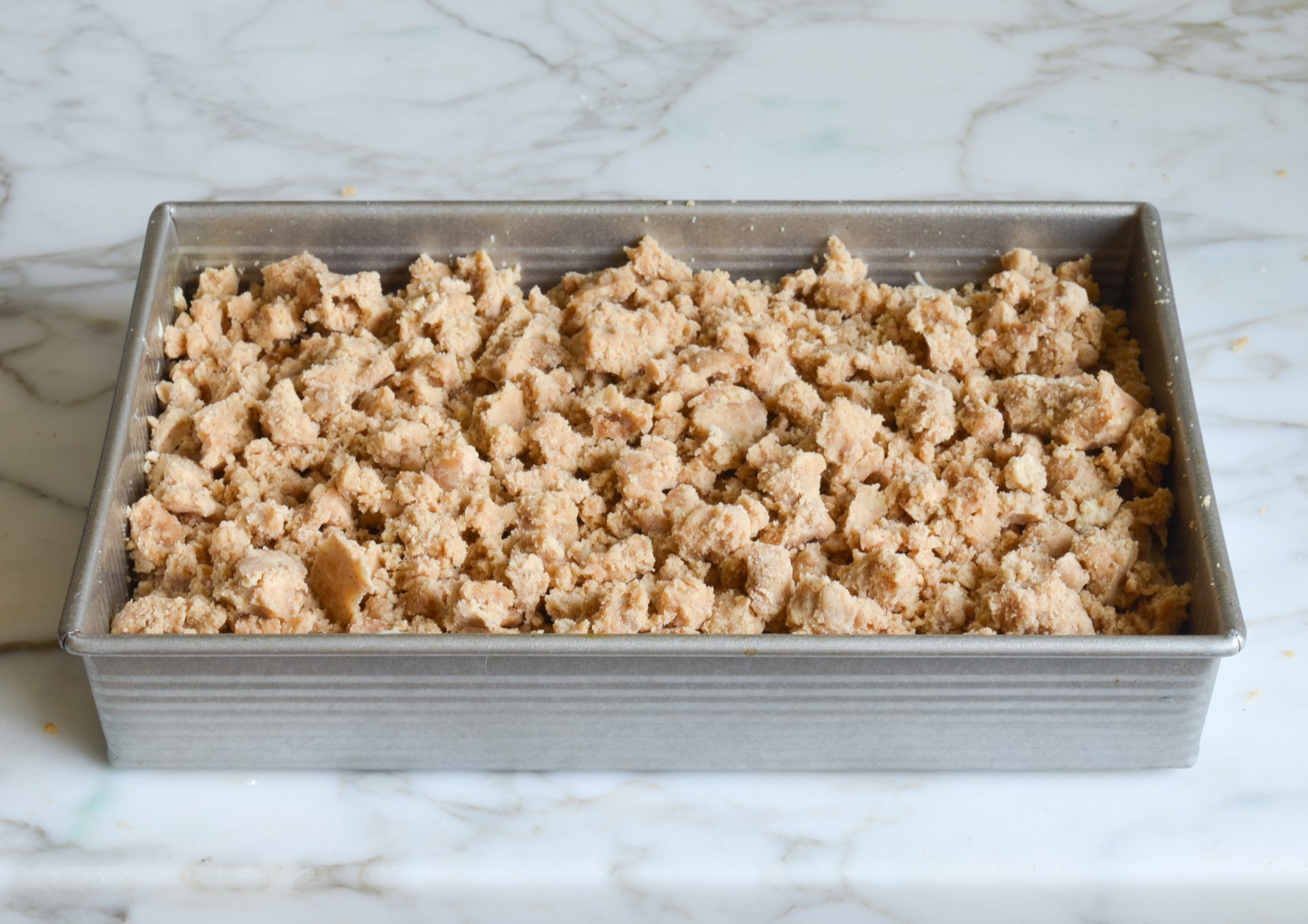 Adding the crumb topping on top of the batter.
