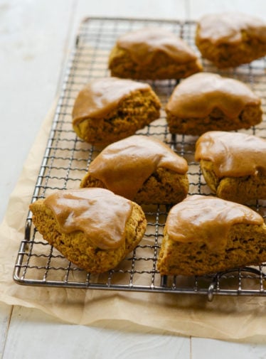 Pumpkin scones with spiced pumpkin glaze on a wire rack.