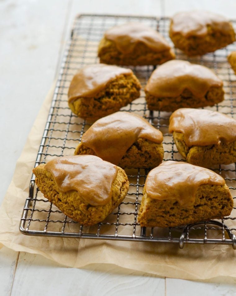 Pumpkin scones with spiced pumpkin glaze on a wire rack.