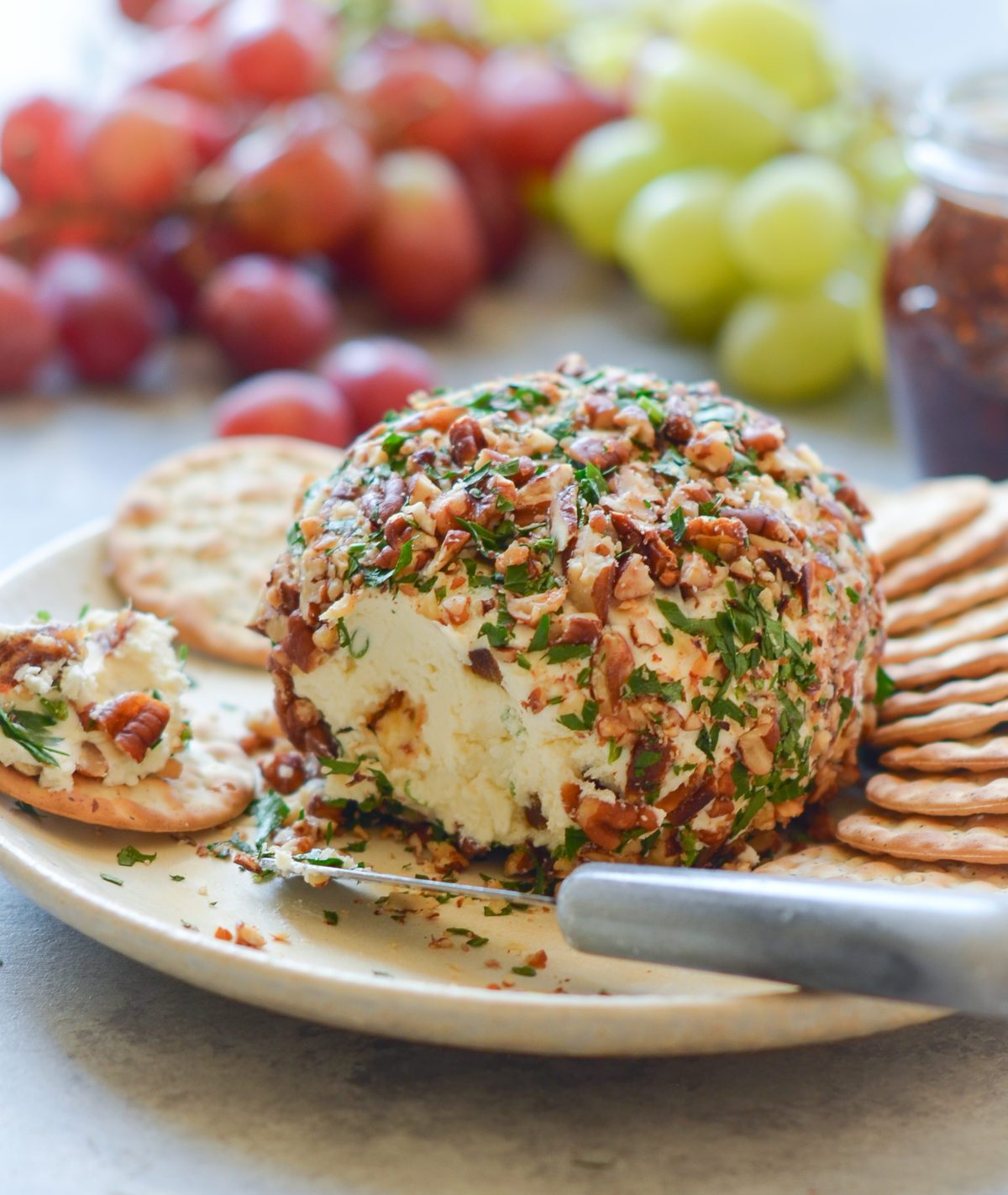 cheese ball on platter with crackers and grapes