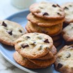 Stacks of thin and crisp chocolate chip cookies on a plate.