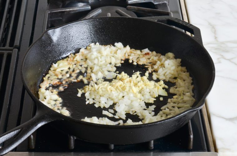 adding ginger and onions to skillet