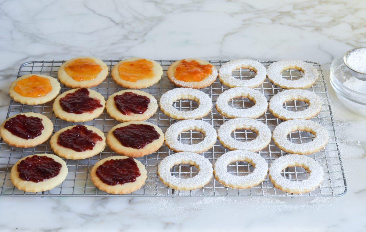 spreading cookies with jam and dusting with Confectioners' sugar