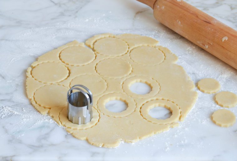 using cookie cutters to cut the rolled dough