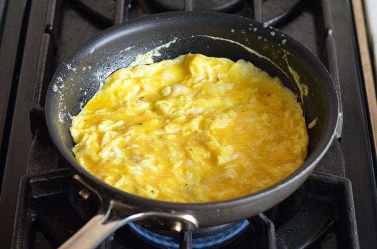 spreading the partially cooked eggs into an even layer 