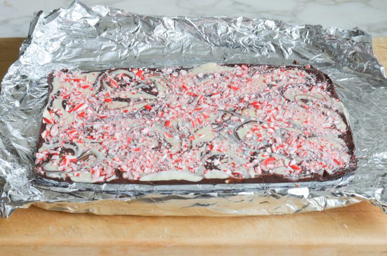 using the foil overhang to remove the sheet of peppermint bark from the ban