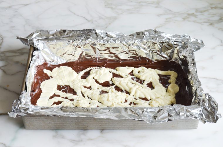 drizzling white chocolate over chocolate layer
