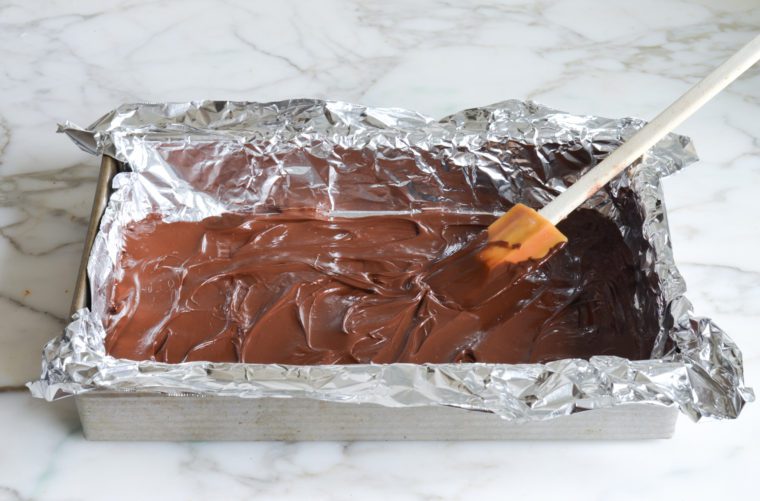 spreading melted chocolate in foil-lined cake pan