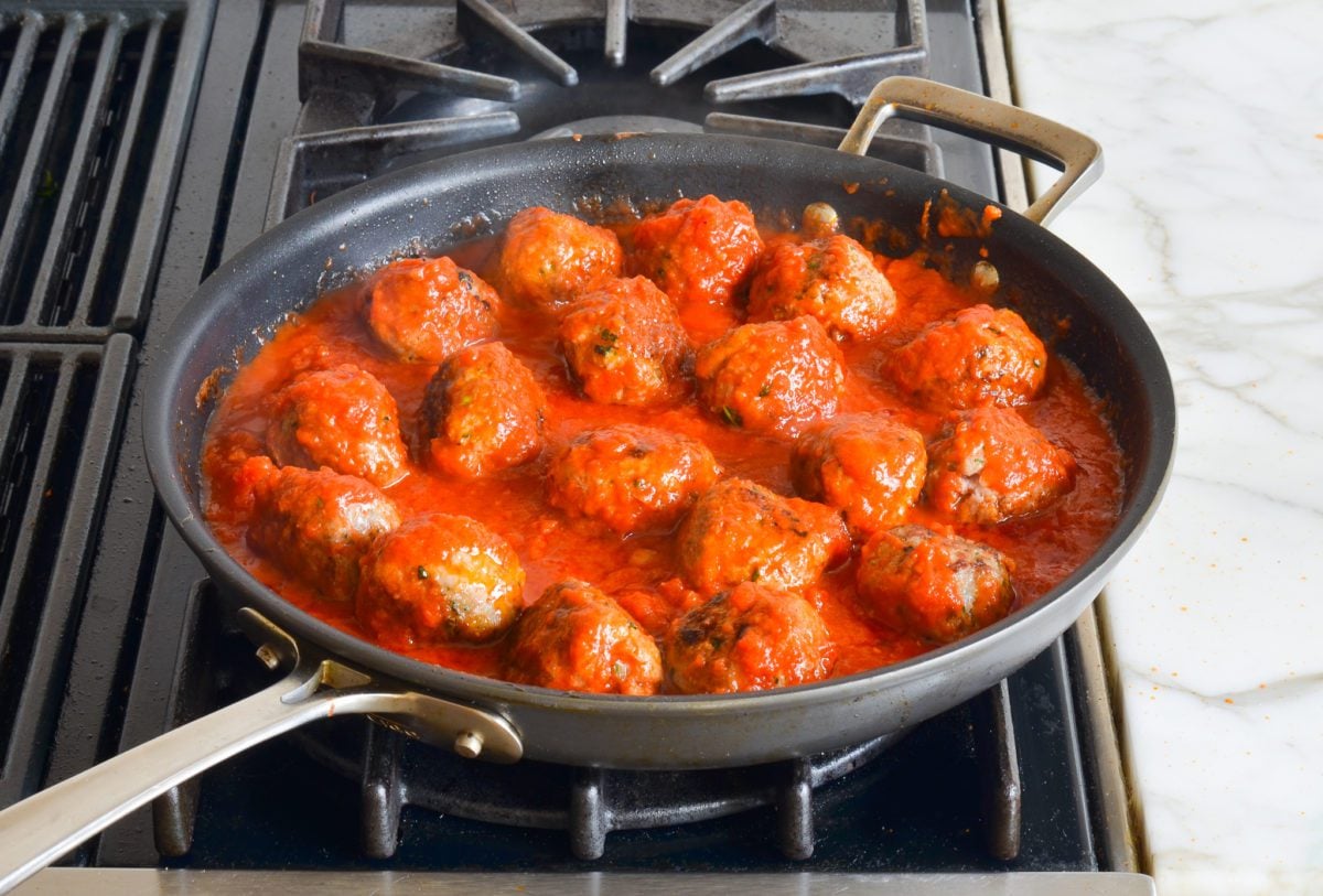 adding sauce to meatballs