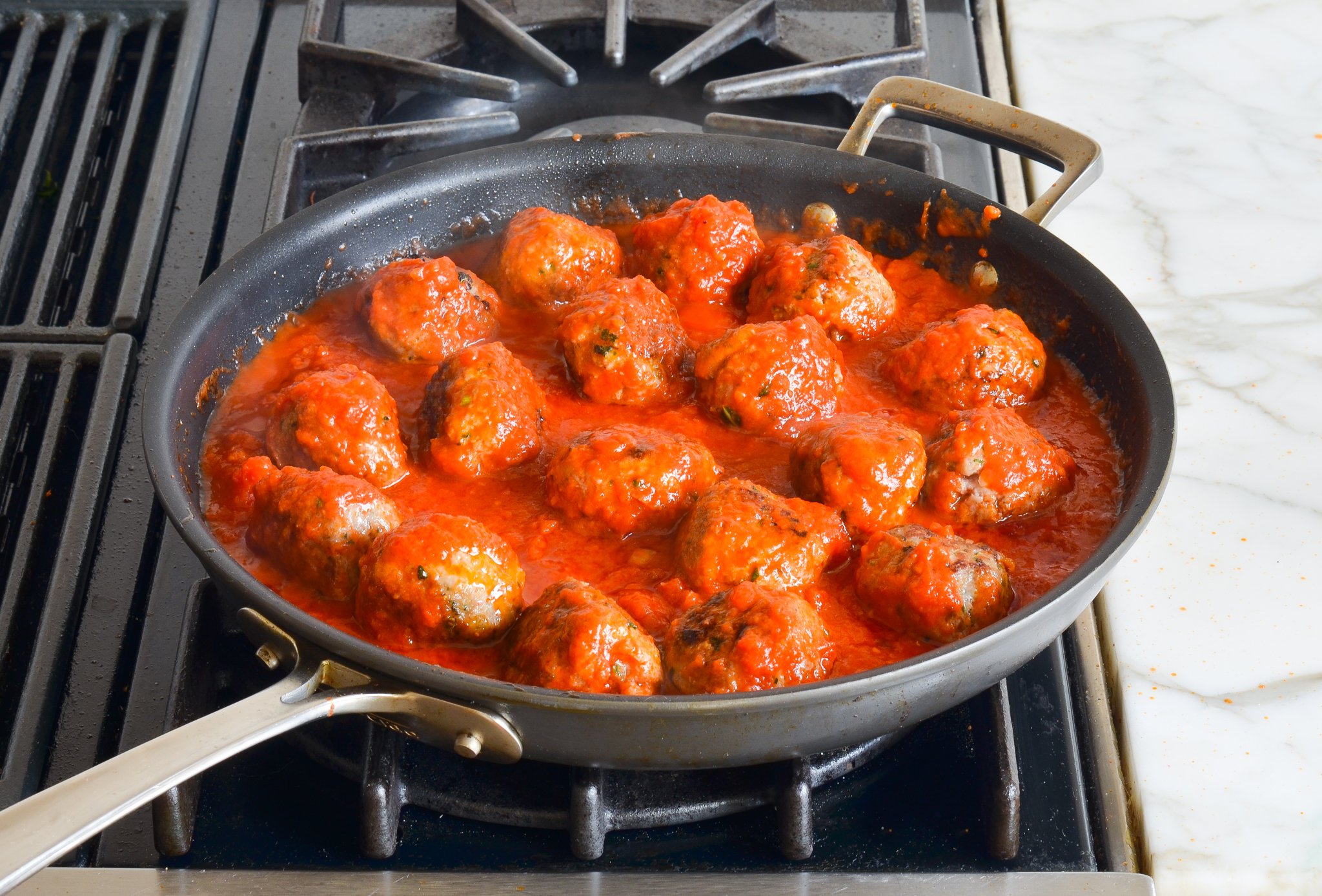 Sauce added to turkey meatballs in a skillet.