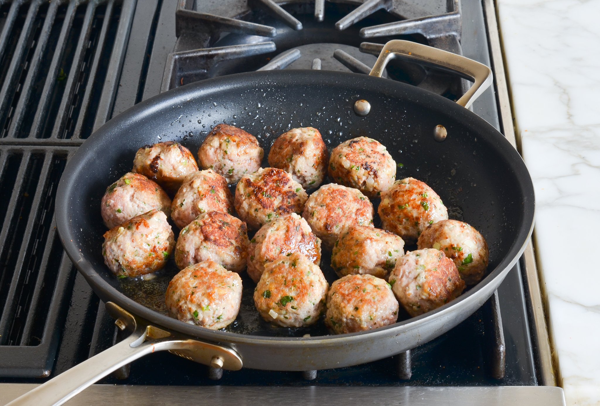 Browned turkey meatballs cooking in a skillet.