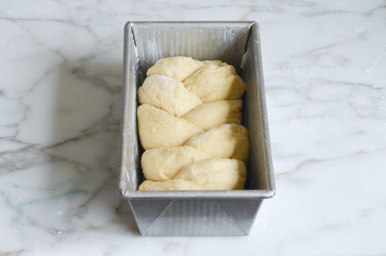 Braided brioche dough in a bread pan.