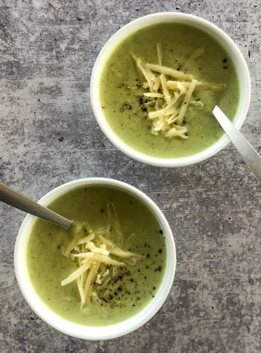 Two bowls of cream of broccoli soup with cheddar.