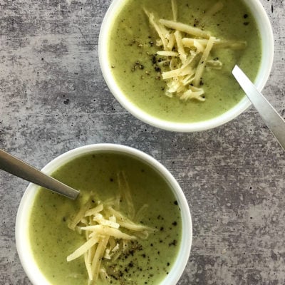 Two bowls of cream of broccoli soup with cheddar.