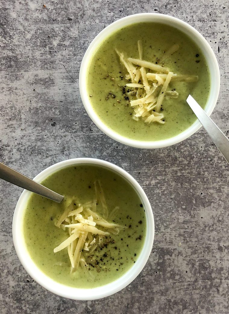 Two bowls of cream of broccoli soup with cheddar.
