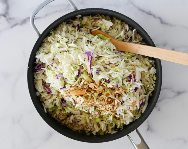 adding coleslaw and soy sauce to skillet