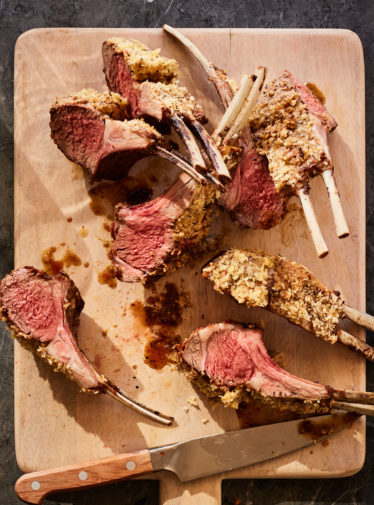 Lamb with Dijon and panko crust on a cutting board.