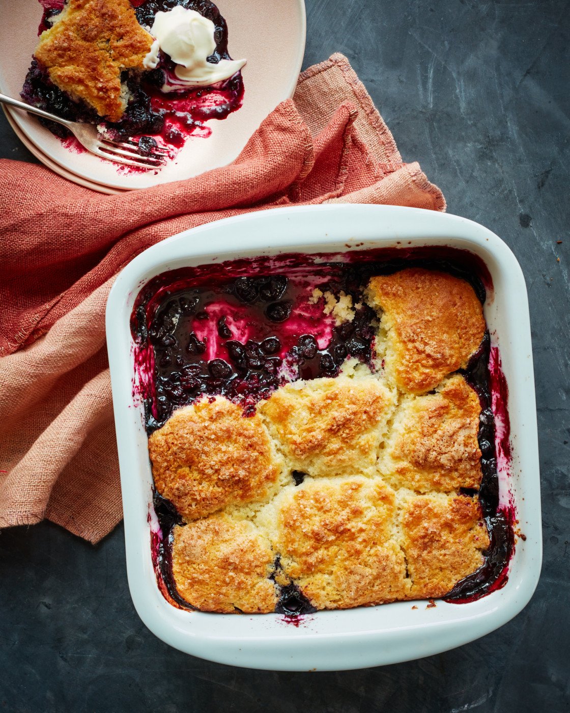 Partially-served blueberry cobbler in a baking dish.
