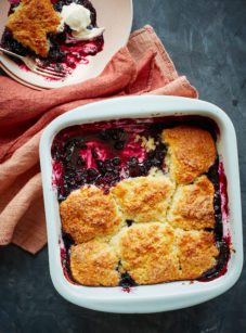Partially-served blueberry cobbler in a baking dish.