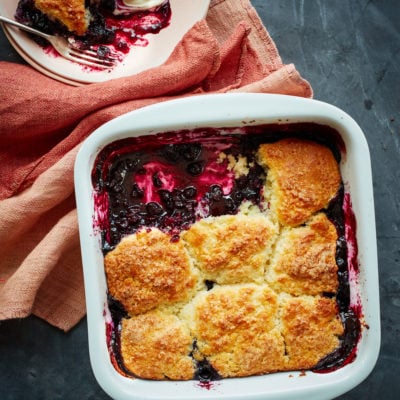 Partially-served blueberry cobbler in a baking dish.