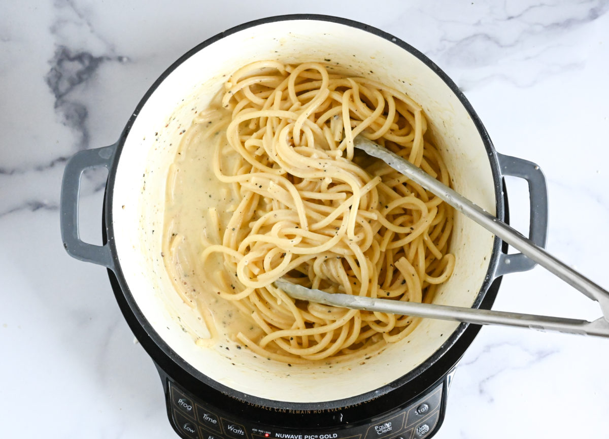 tossing pasta with sauce over low heat